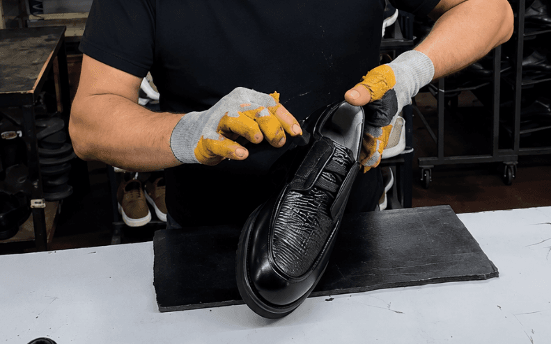 A person polishing a black leather shoe with gloved hands